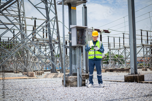 Wallpaper Mural Engineer is working at high voltage substation wearing safety gear and inspecting electrical equipment with focus and care in outdoor industrial environment Torontodigital.ca