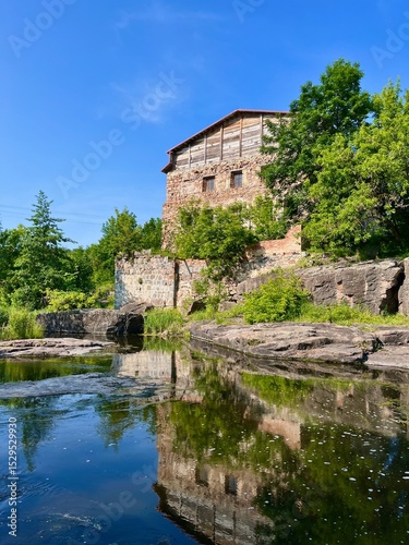 A unique view of an old mill towering over a river in the Butsky Canyon. Its stone walls and wooden superstructure blend seamlessly into the rocky landscape, reflecting in the water.