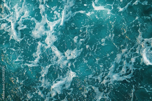 Top view of ocean surface with white sea foam and sun reflections. Clear turquoise water. Natural texture. Clean and refreshing summer atmosphere. Perfect for backgrounds and nature concepts. Banner