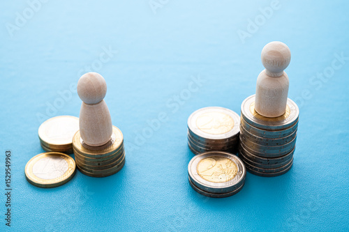 Concept of unequal pay in the workplace between men and women. Wooden figures on piles of coins.