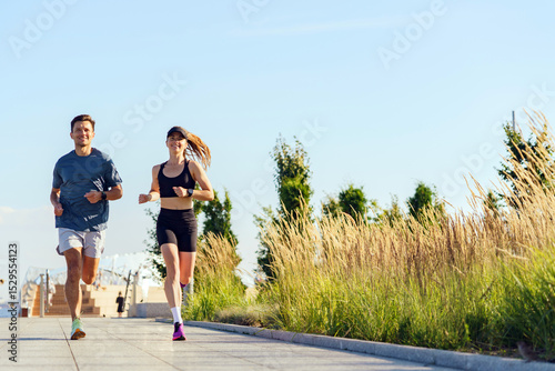 Friends Enjoy a Sunny Morning Jog Along a Scenic Pathway Surrounded by Lush Greenery and Bright Blue Skies