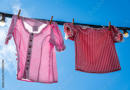 Colorful clothes drying on a line amidst lush green grass in a rural area during bright daytime