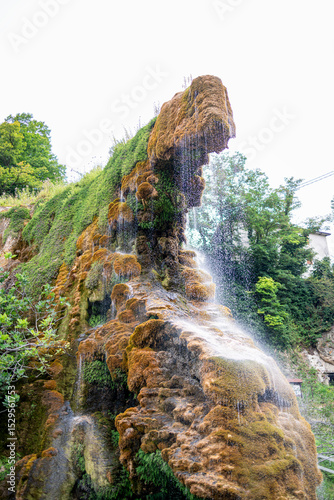 The Grotte di Labante waterfall flows over moss-covered rocks, creating a unique natural formation in the Italian Apennines