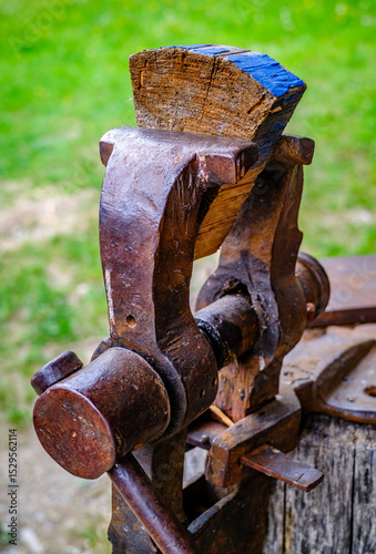 Vintage woodworking vise showcased in a rustic workshop setting with tools and cabinets arranged behind it