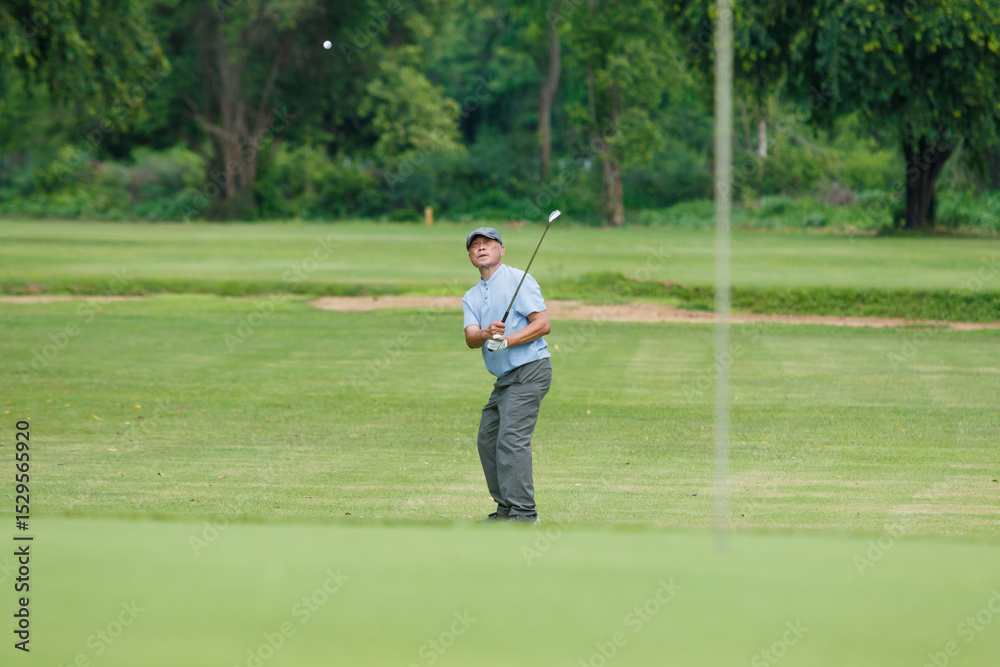 Elderly Asian man enjoying the morning round of golf in soft and warm sunlight. Elderly Asian man enjoying the morning round of golf in soft and warm sunlight.