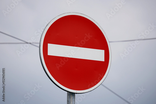 No entry traffic sign displayed clearly on the roadside. A bold red circle with a white bar, symbolizing restricted access and traffic regulation. Ideal for safety, transport, and navigation visuals.
