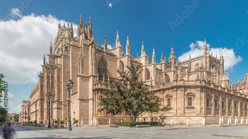 The Seville Cathedral and Giralda Tower timelapse hyperlapse in Seville, Spain. The largest gothic cathedral in the world, UNESCO heritage site, located on Avenue de la Constitucion under a blue sky