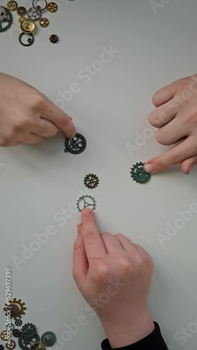 Hands create intricate designs with gears at a crafting table during a creative workshop