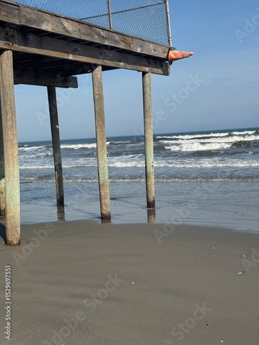Low tide beneath a wooden beach pier with waves rolling in at Wildwood, New Jersey