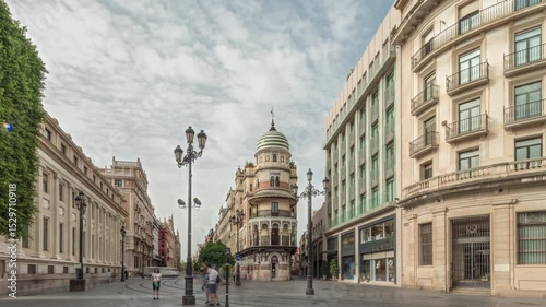 Pedestrians walking along Avda. de la Constitucion, major avenue in Casco Antiguo district of Seville, Spain. Timelapse hyperlapse with Edificio de la Adriatica, historical buildings and passing trams
