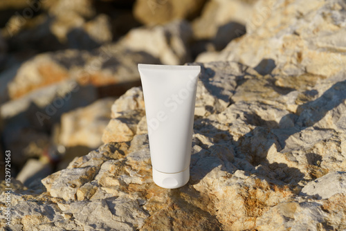 White mockup cosmetic tube placed on a rocky surface under daylight. The scene highlights the product for face, suggesting skincare or beauty context