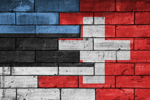 colourful painted big national flag of switzerland and flag of estonia on a massive old brick wall background. concept