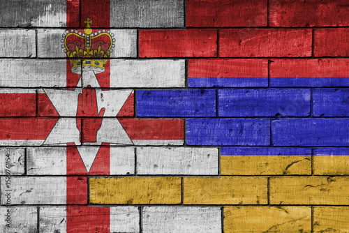 colourful painted big national flag of armenia and flag of northern ireland on a massive old brick wall background. concept