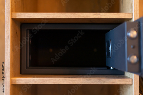 A lockable safe is positioned in an open wooden cabinet, showcasing its depth and design. Ideal for securing important items in a residential setting