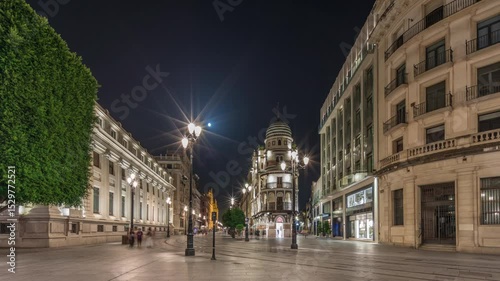 Avenida de la Constitucion night timelapse hyperlapse in Seville, Spain. Iconic Adriatica building glowing at evening. Historic architecture with modern streetlights, pedestrians and urban atmosphere
