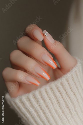 Modern and minimalist touch: Hand with almond-shaped nails, featuring a nude design with vibrant orange tips and a delicate crescent-shaped applique. Ideal for beauty themes, nail art trends and conte