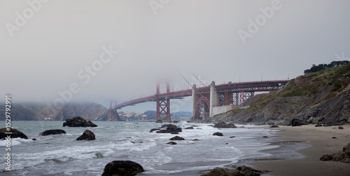 The Golden Gate Bridge in San Francisco, California disappears into the fog, as seen from the beach.