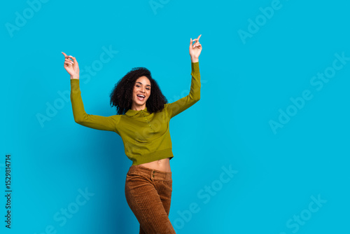 Cheerful woman in casual fashion celebrating against vibrant blue background expressing joy with raised arms