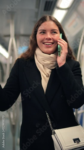 Joyful female passenger engaged in a lively conversation on her smartphone while traveling on the subway, showcasing the ease of communication and connection in her daily life during transit