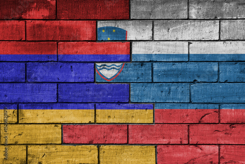 colourful painted big national flag of slovenia and flag of armenia on a massive old brick wall background. concept