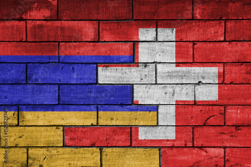colourful painted big national flag of switzerland and flag of armenia on a massive old brick wall background. concept