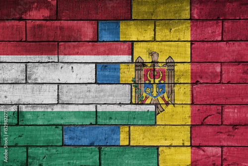 colourful painted big national flag of moldova and flag of hungary on a massive old brick wall background. concept