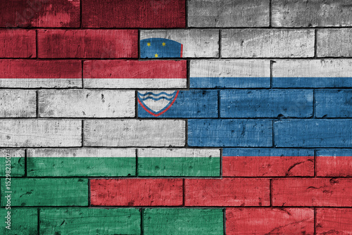 colourful painted big national flag of slovenia and flag of hungary on a massive old brick wall background. concept