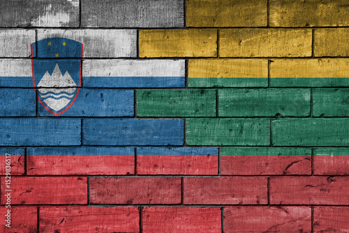 colourful painted big national flag of lithuania and flag of slovenia on a massive old brick wall background. concept