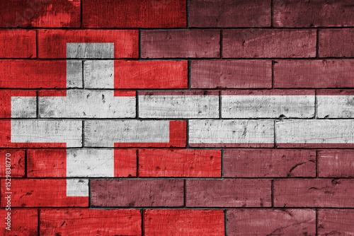 colourful painted big national flag of latvia and flag of switzerland on a massive old brick wall background. concept