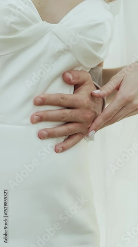 Vertical video. An Intimate Maternity Moment Featuring Two Hands Gently Placed on a Beautiful Expecting Belly