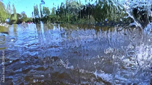 Stream of water flowing from lake to lake, play of light and glare of light in falling water