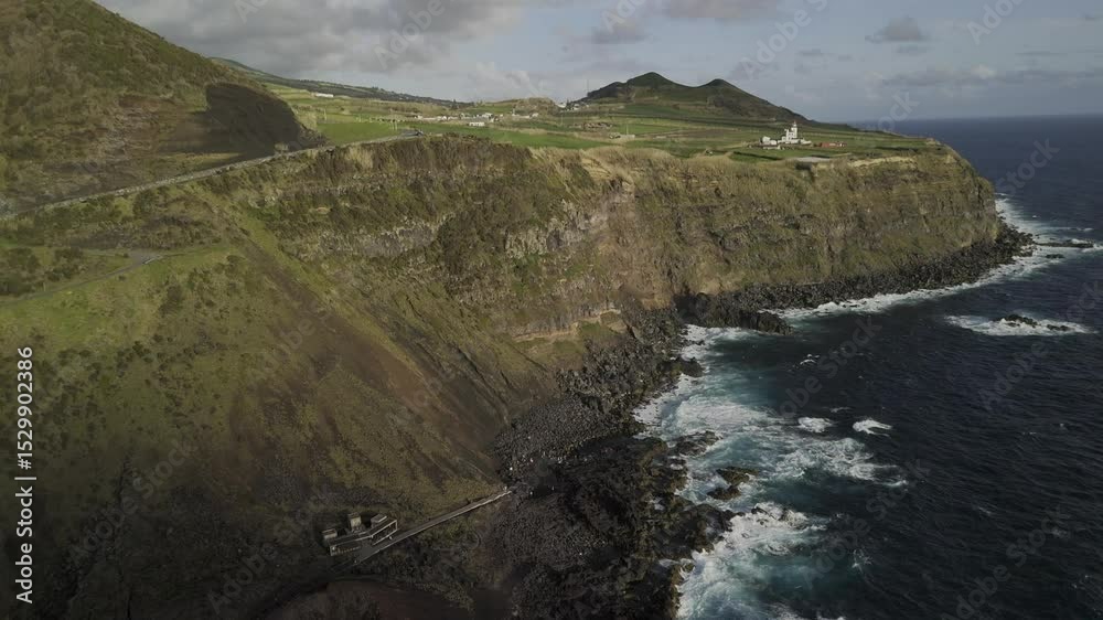 Drone orbits left high over Ponta da Ferraria natural thermal pools with lighthouse on cliff in Sete Cidades region, Sao Miguel, Azores, Portugal
