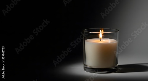 Burning Candle in Glass Holder Symbolizing Remembrance Hope and Tranquility on Dark Background with Bright Light