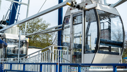 Cable cars stand ready for adventure at an amusement park in springtime, inviting visitors to experience a scenic ride above the ground