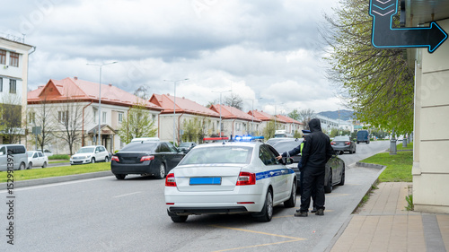 Police officer conducts traffic stop on highway with vehicles in background on cloudy day