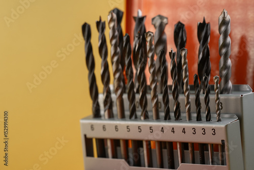 Collection of metal drill bits organized in a holder showcasing various sizes and styles for woodworking or metalworking tasks