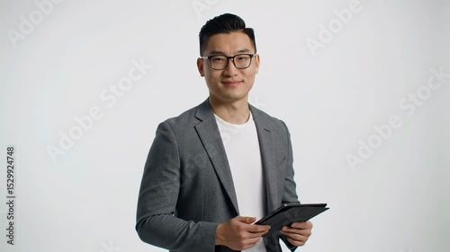 Confident asian businessman in glasses holding a tablet against a white background