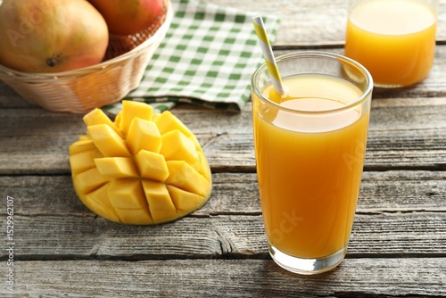 Fototapeta Naklejka Na Ścianę i Meble -  Tasty mango juice in glass and fresh fruits on wooden table, closeup