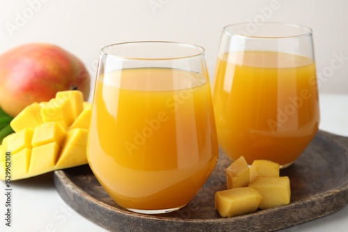 Fototapeta Naklejka Na Ścianę i Meble -  Tasty mango juice in glasses and fresh fruits on white table, closeup
