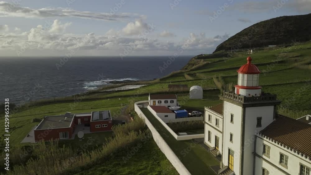Drone flies north past the Ferraria Lighthouse on a windy day at sunset in Sete Cidades region, Sao Miguel, Azores, Portugal
