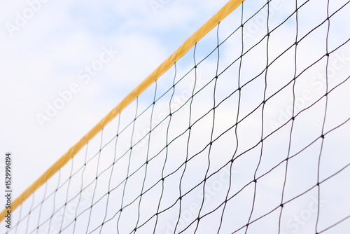 Beach volleyball net close-up. Volleyball net fragment on the beach against the sky. Sport, beach volleyball. Active recreation concept. Background. Yellow net detail. Sports ground