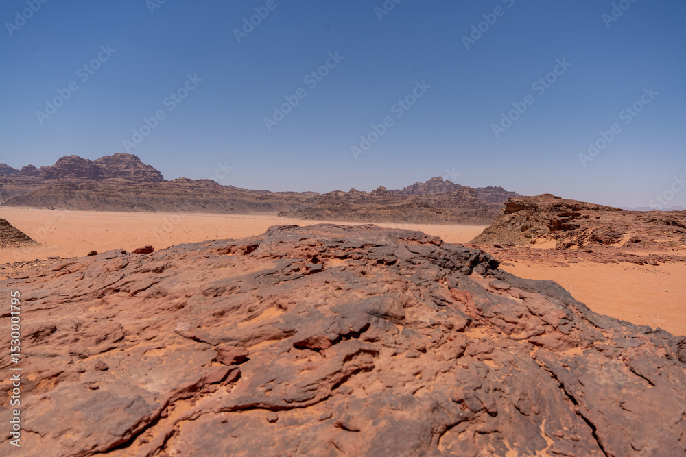Naklejka premium Desert Landscape: A captivating panoramic view of a vast desert under a clear, azure sky, showcasing rugged terrain and a sense of expansive space.