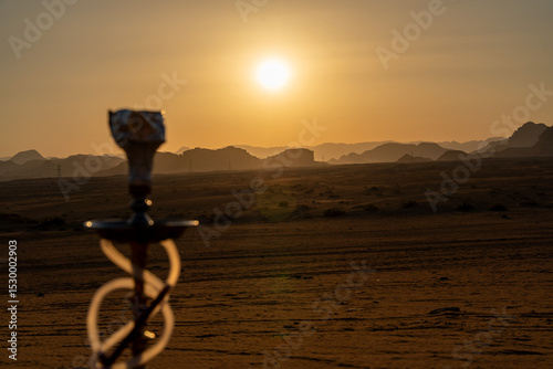 Sunset Shisha Serenity: A captivating capture of a shisha pipe silhouette against the backdrop of a sun-kissed landscape, where the rich hues of the setting sun blend with the textures of the scene.