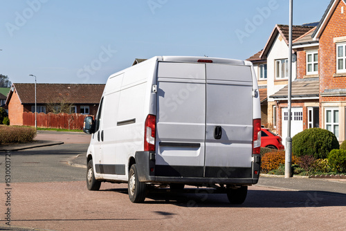 Fototapeta Naklejka Na Ścianę i Meble -  Rear view of an unbranded white van on a residential street. Ideal for illustrating logistics, courier services, online shopping deliveries, or local tradesperson concepts. Copy Space