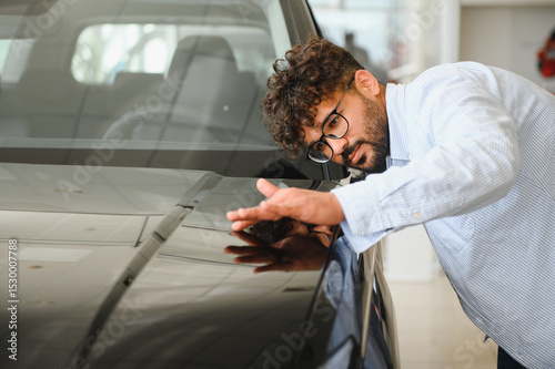 Tapeta Customer carefully inspecting new car at dealership