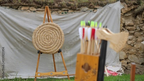 focusing on medieval straw target on a stand with arrows with red tips in the foreground