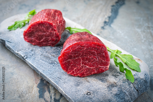 Raw beef fillet steak offered as close-up on natural stone plate