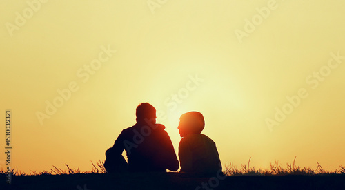 black silhouette of Young adult romantic couple sitting together on yellow sunset sunrise sky background backdrop. evening date. sun disk between pair. unrecognizable person. Horizon hill line
