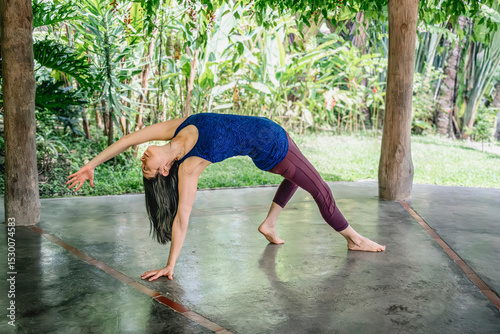 Woman practicing wild thing yoga pose in tropical retreat
