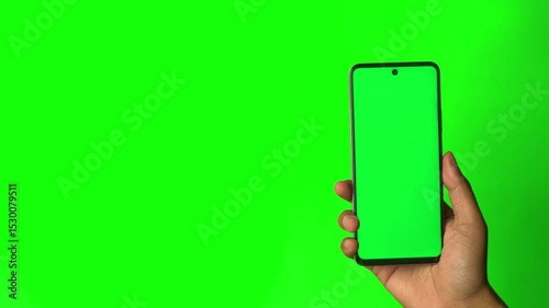 Hand holding smartphone with chroma green screen. Green background